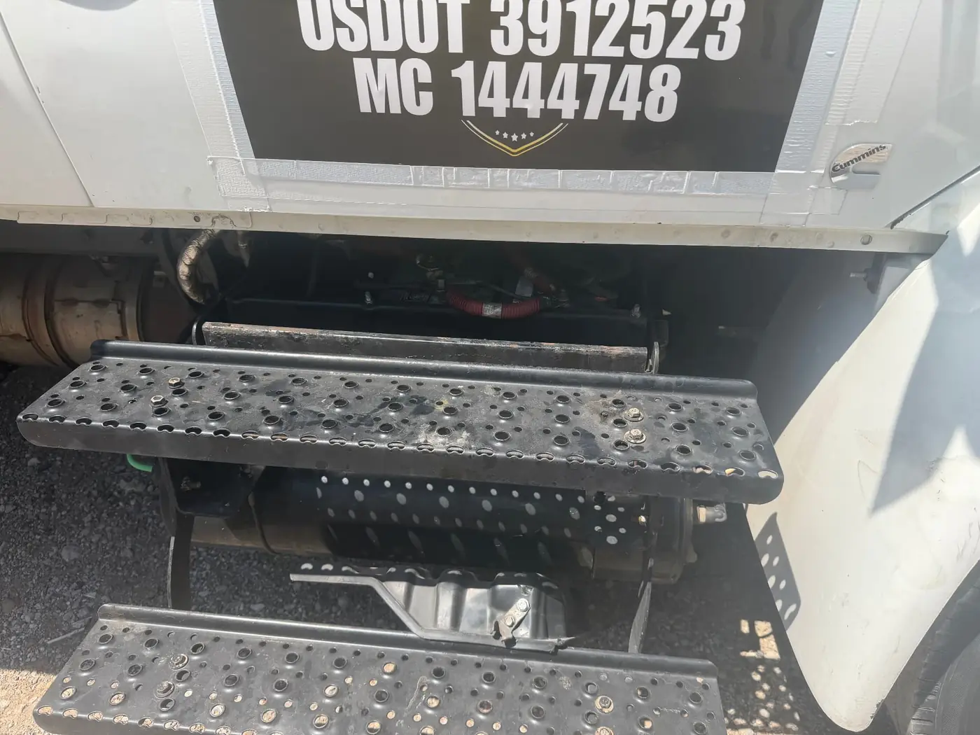 Battery box open on a white commercial box truck with USDOT and MC numbers visible during a mobile battery replacement in Dallas-Fort Worth.