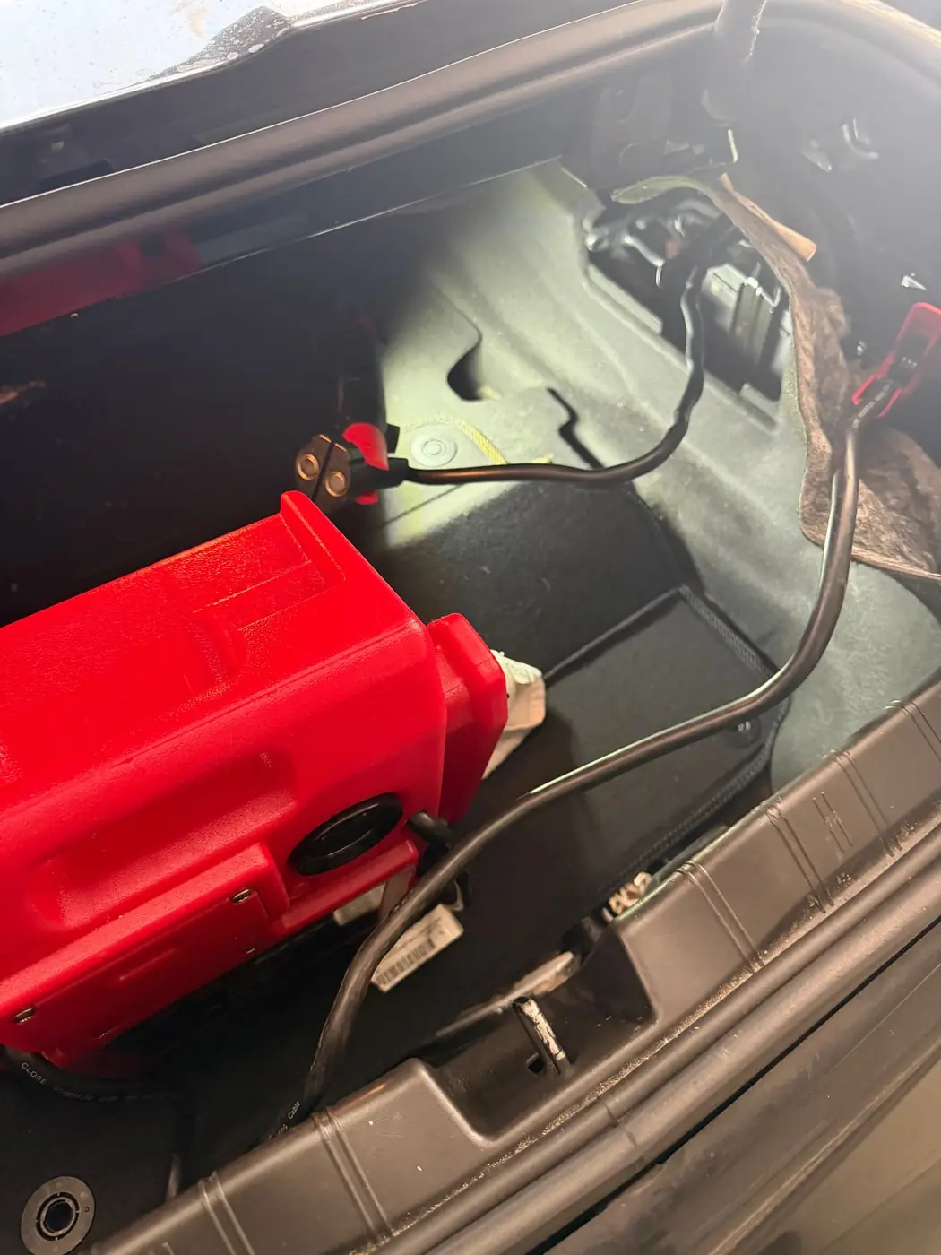 Jump pack clamps on a trunk-mounted car battery during a mobile jump start in Dallas, Texas.