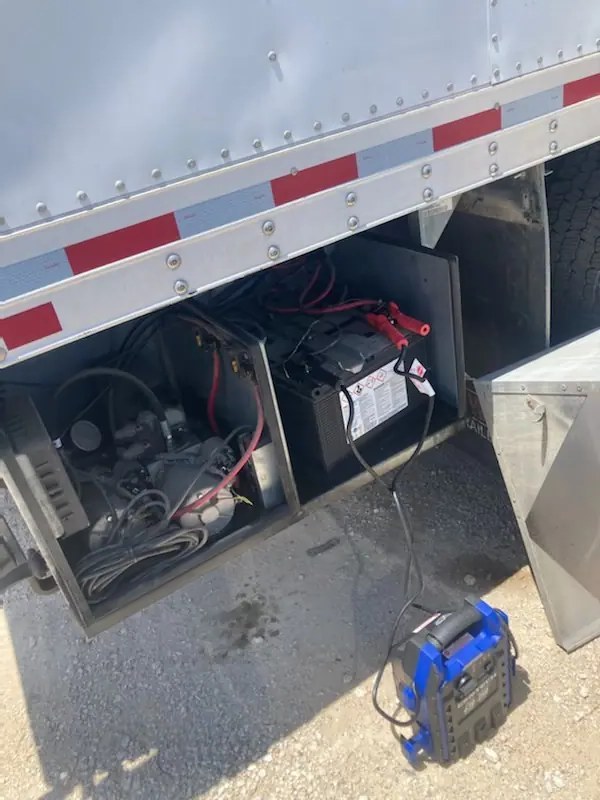Semi tractor-trailer jump start on a Dallas-Fort Worth roadside with heavy-duty cables on the battery box