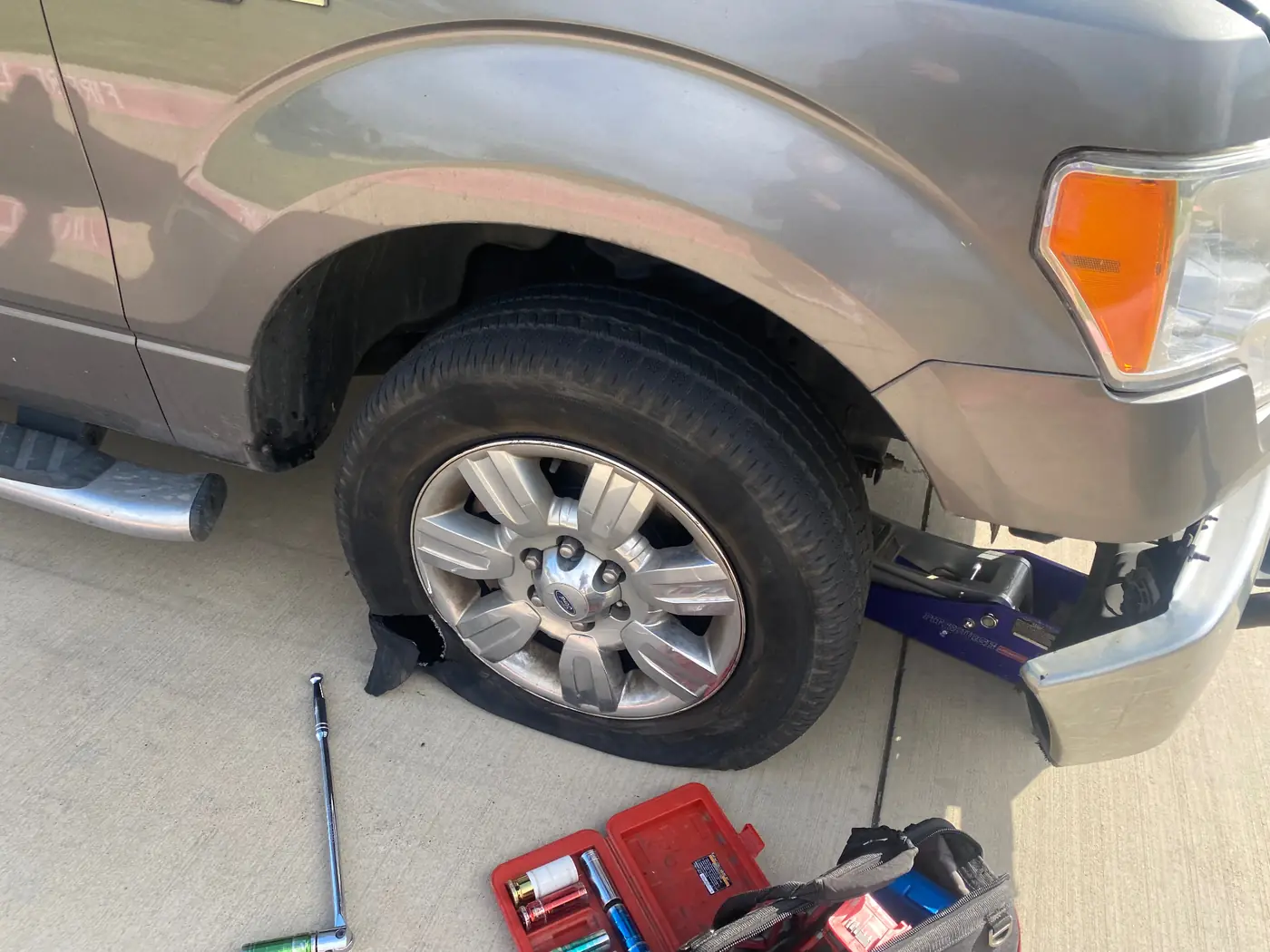 Ford F-150 raised on a floor jack during a mobile tire service call in Dallas-Fort Worth.
