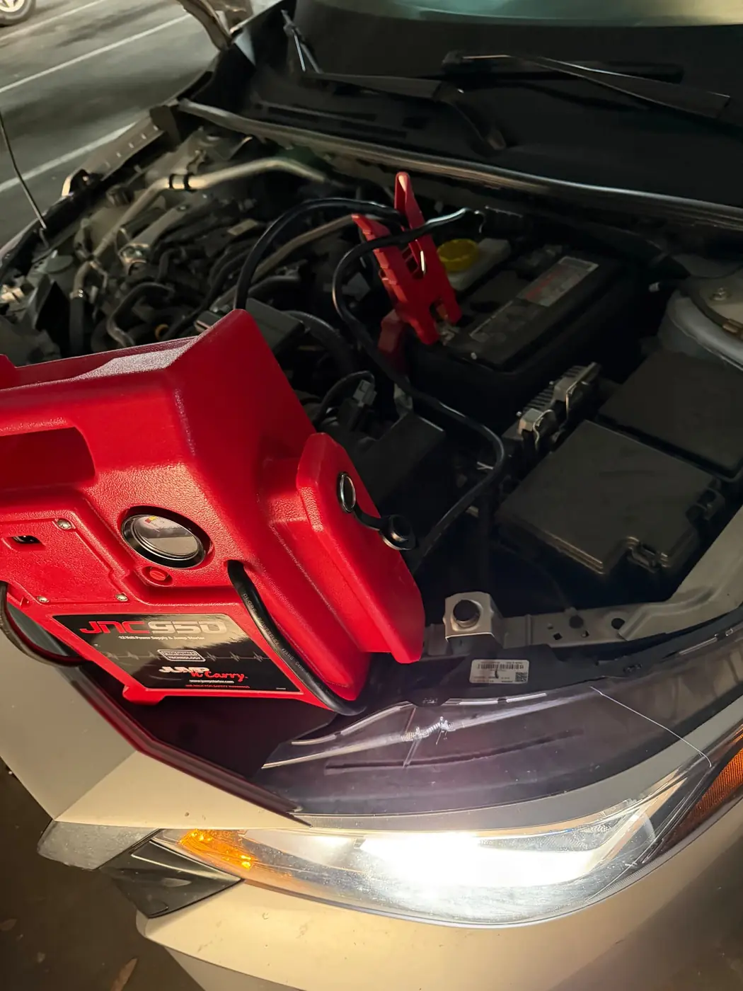 JNC950 jump pack connected to a Nissan Sentra battery during a 24/7 mobile jump start in Dallas-Fort Worth.