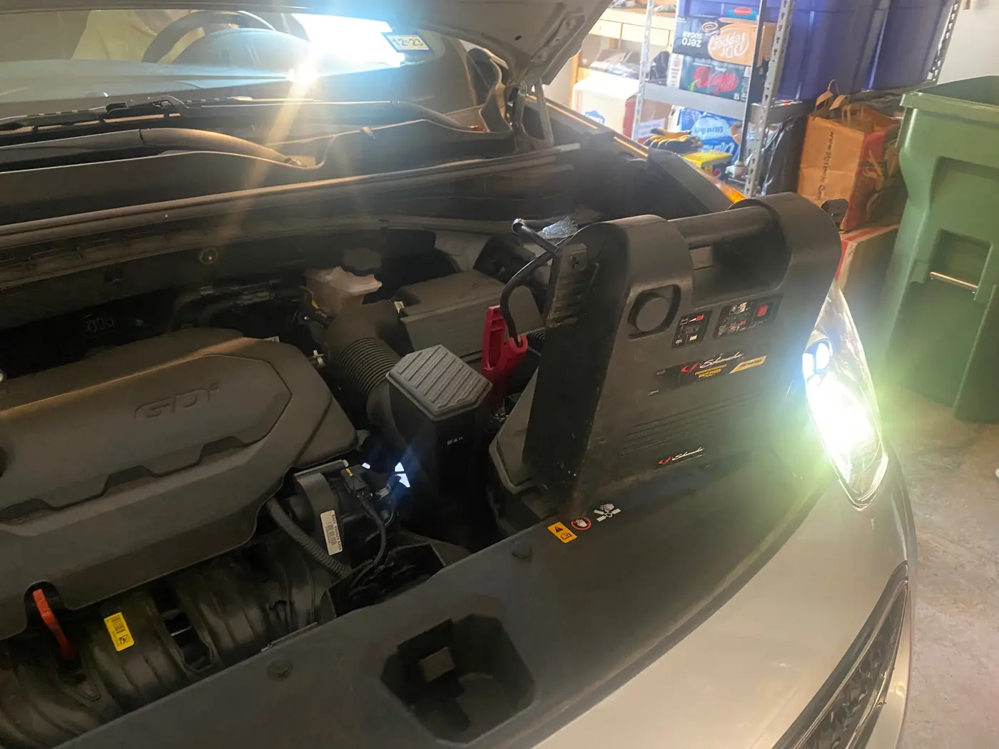 Jump pack clamps on the battery of a Kia GDI engine bay during a mobile jump start in Fort Worth, Texas.