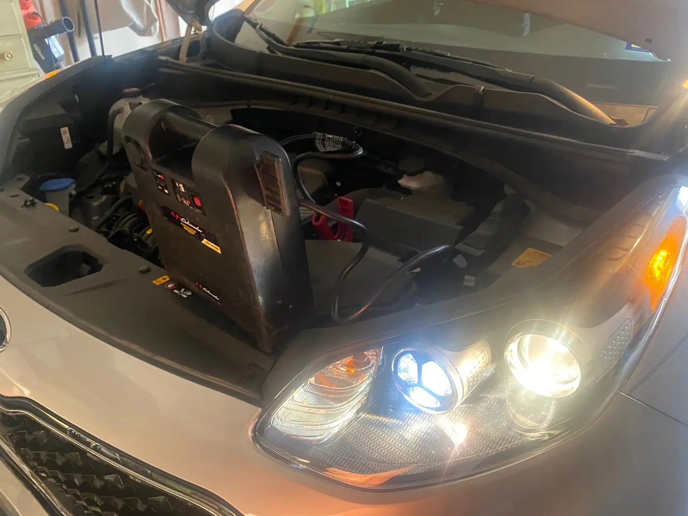 Technician jump starting a Kia/Hyundai in an Arlington, Texas parking lot with a commercial jump pack on the battery.