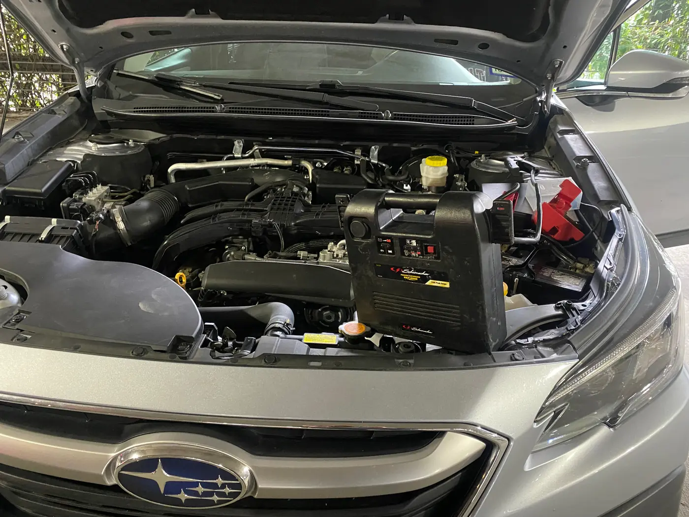 Subaru Outback with the hood up and a jump pack on the battery during a mobile jump start in Plano, Texas.