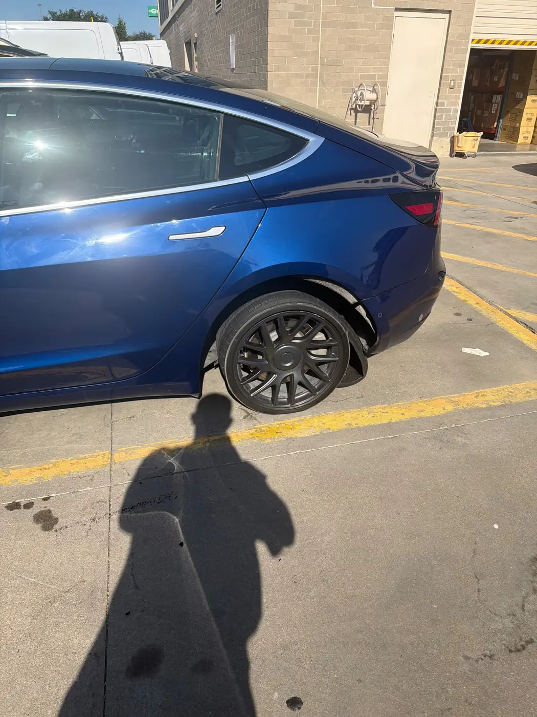 Blue Tesla Model 3 with a destroyed rear tire off the bead and shredded sidewall rubber hanging in the wheel well before a mobile tire replacement in DFW