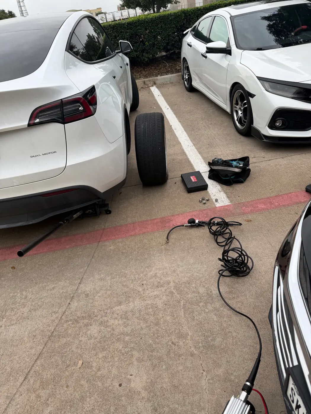 Tesla Model Y lifted for a mobile tire change in Dallas-Fort Worth with the wheel removed.